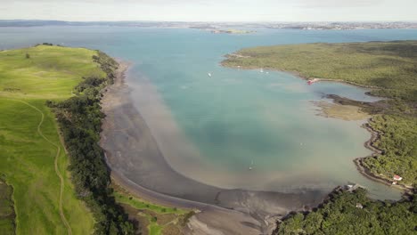 aerial pull back over land bridge between motutapu island and rangitoto volcano