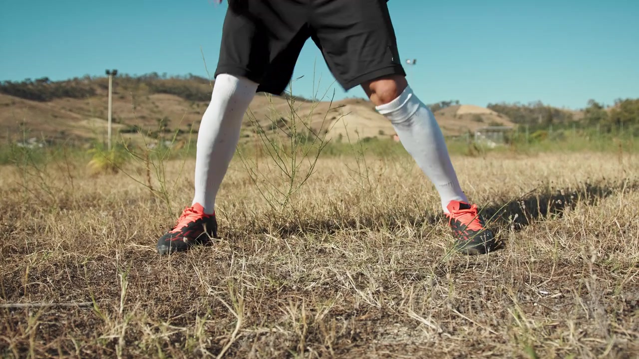 Uomo con scarpe da calcio che si riscalda su erba gialla