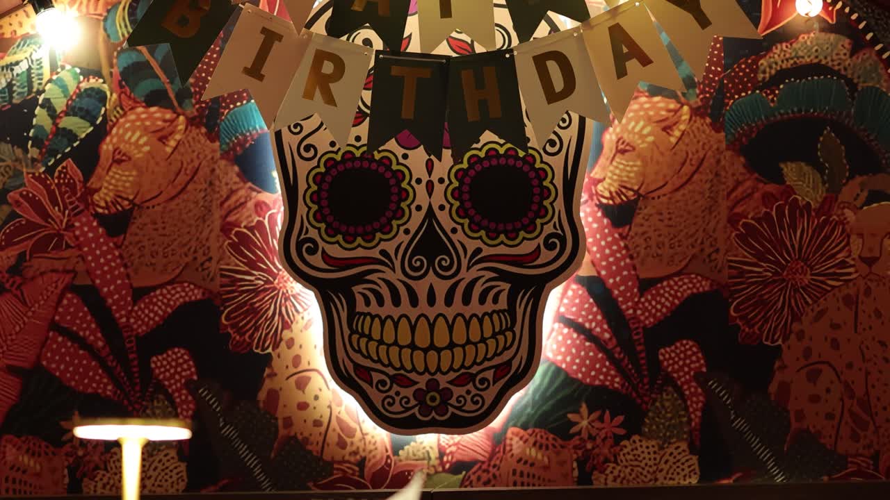 Colorful birthday setup featuring skull artwork and balloons in a lively Bangkok restaurant. Warm lighting enhances the festive atmosphere