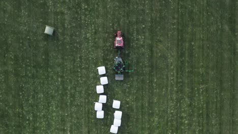 machine finished wrapping hay bale dropping it on green field for drying, fermentation process for fodder