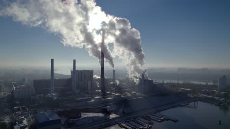 aerial descend shot of a coal-fired heating power station with thick white smoke coming from the chimney, environmental pollution concept