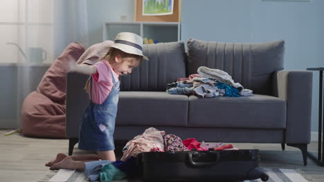 girl puts clothes into bag and imitates flying plane at home