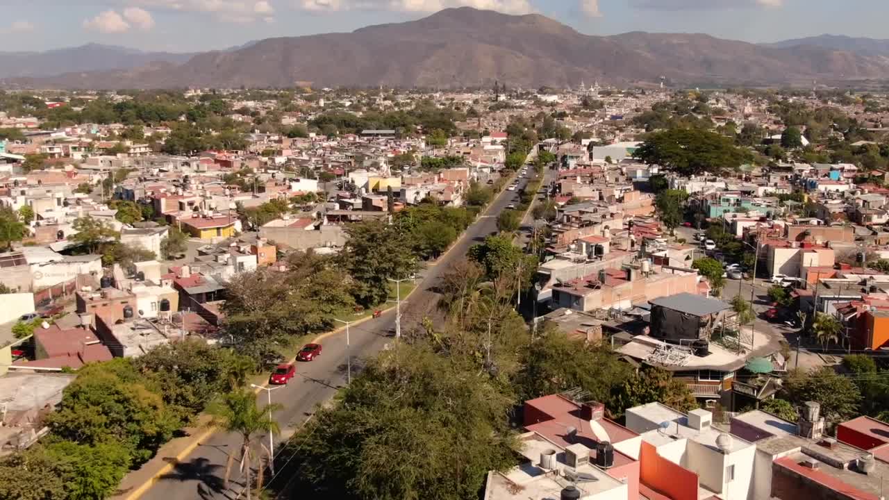 Dynamic aerial timelapse showcasing the vibrant urban landscape of Tuxpan, Jalisco. Captures bustling streets, colorful architecture, and distant mountains under a clear blue sky