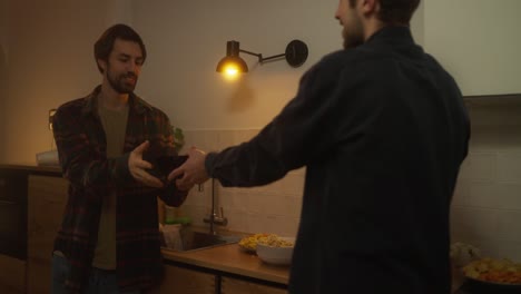 dos amigos hombres hablando y comiendo bocadillos en la cocina