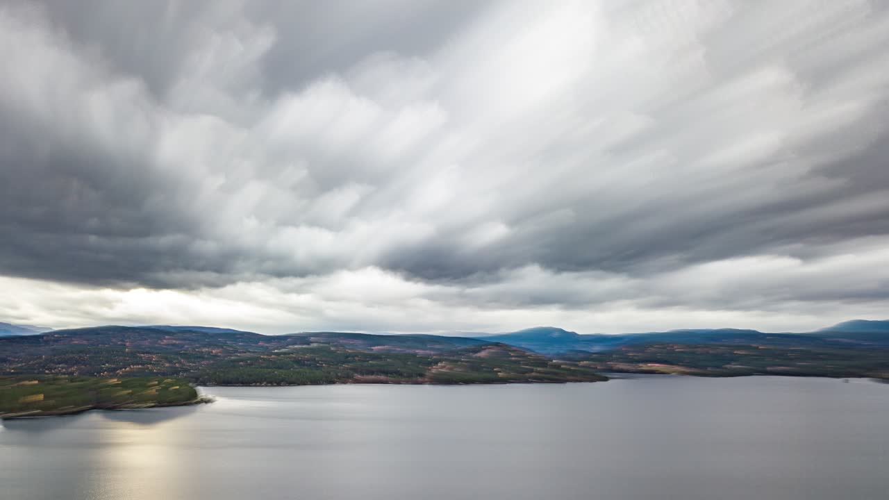 espesas nubes blancas que se precipitan sobre las tranquilas aguas oscuras del fiordo