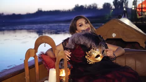 beautiful woman with carnival mask riding on gondola.