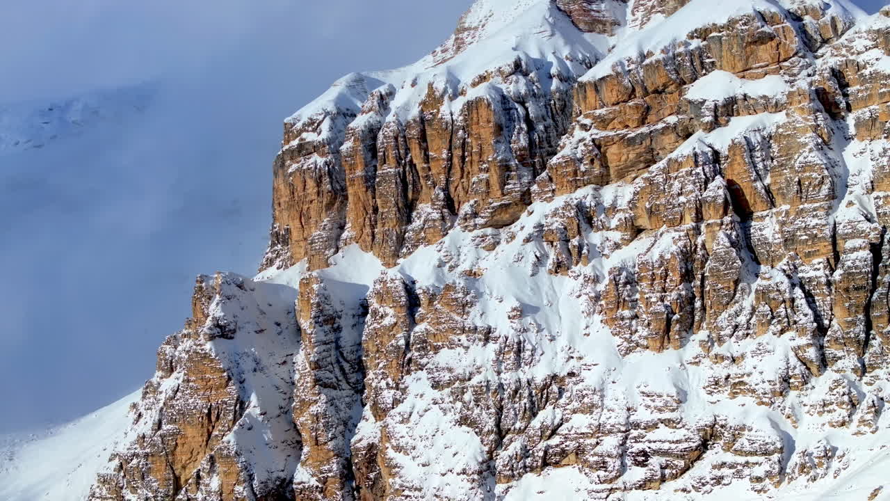 Aerial drone view of snow on the Sassongher mountain in the Dolomites, Italy with the blue sky on the background