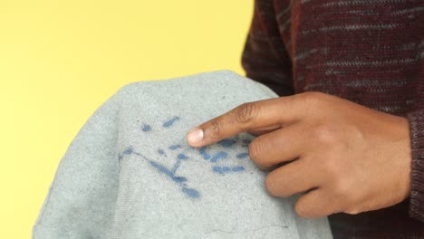 persona señalando una mancha azul en una camisa gris