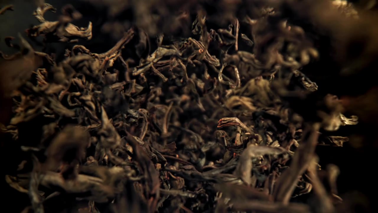 Slow Motion of Dry Tea Leaves Swirling on a Dark Background