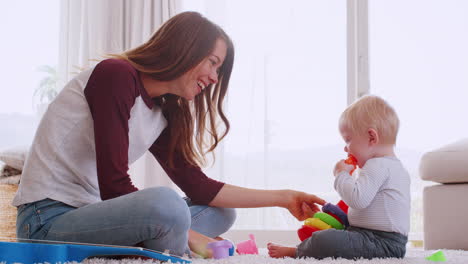 Young-mum-sitting-on-floor-playing-with-son,-side-view