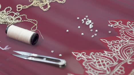 closeup of beads and cotton thread used by dressmaker manufacturing a sari, handcrafted fashion