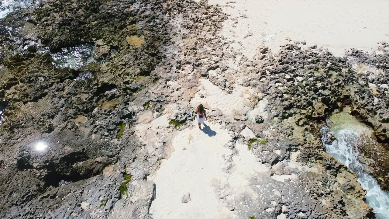 aerial top down of young girl walking on rocky beach in Cozumel Mexico on sunny day