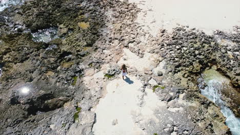 Antena-De-Arriba-Hacia-Abajo-De-Una-Joven-Caminando-En-Una-Playa-Rocosa-En-Cozumel-México-En-Un-Día-Soleado