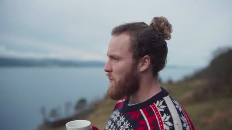un tipo está bebiendo café en una taza afuera con fondo de naturaleza