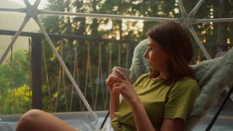 mujer pacífica inspirada en la naturaleza bebiendo bebida caliente en taza en un sillón sola lugar atmosférico para relajarse y disfrutar de la belleza en el desierto cámara lenta