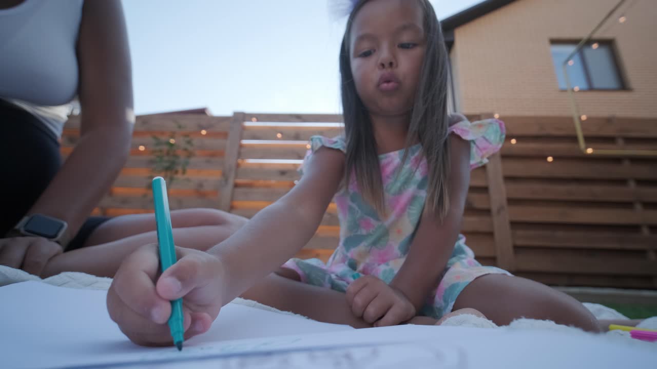 niña dibujando al aire libre con su madre
