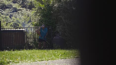 male gardener trimming grass in the garden using grass cutter