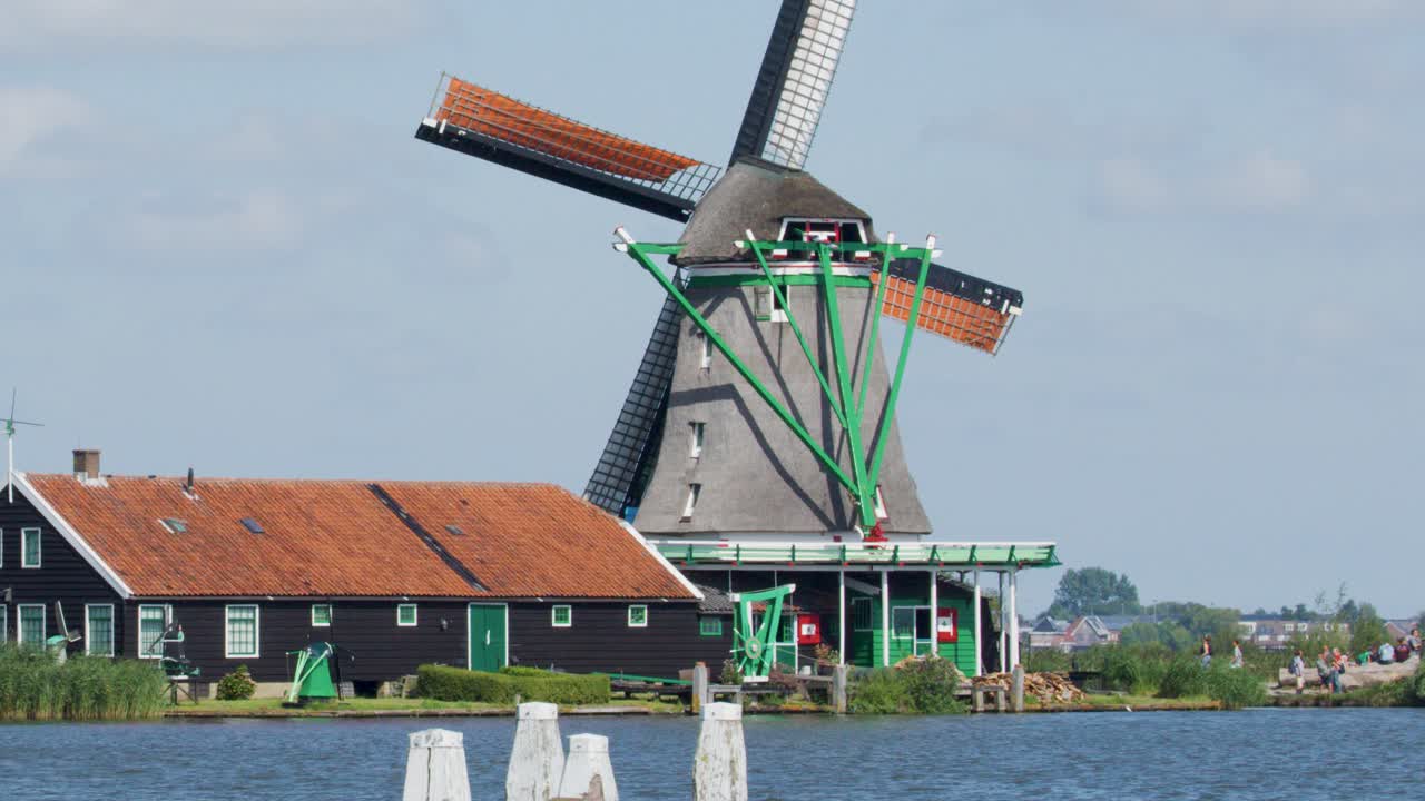 Rotating windmill beside house and canal in countryside