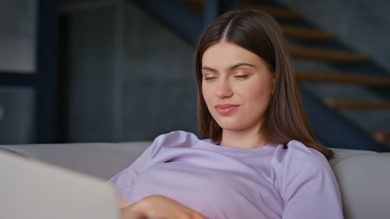 Smiling girl watching laptop movie at home sofa closeup. Happy woman working