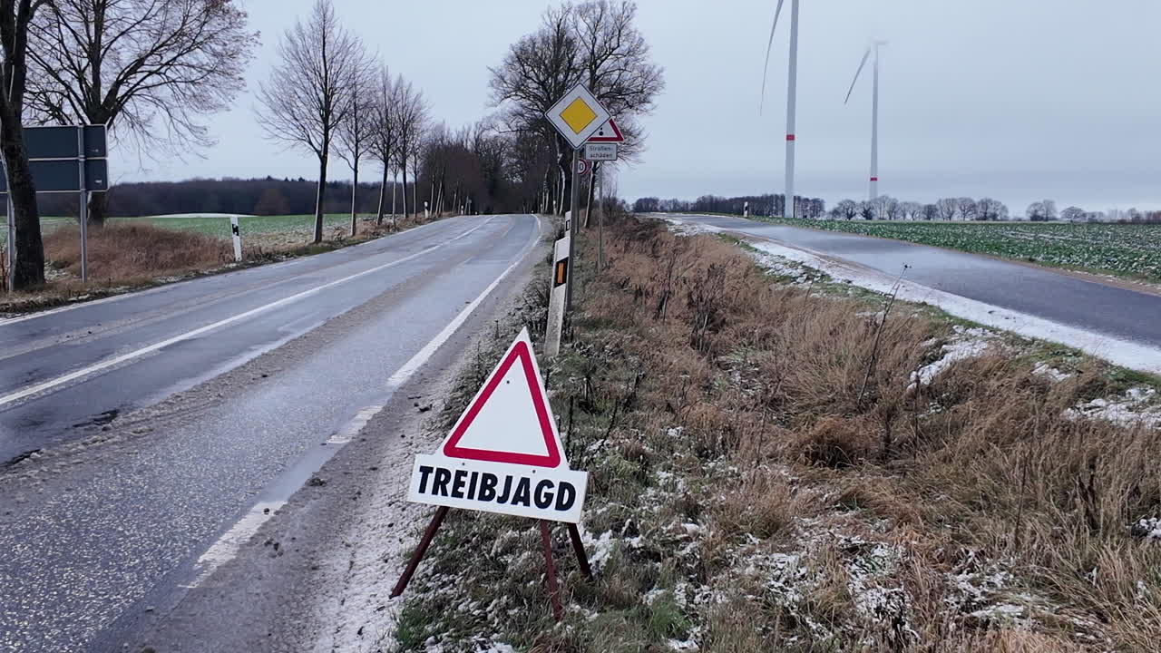 Rural roadside scene in winter featuring a German warning sign reading “Treibjagd,” indicating a driven hunt in progress