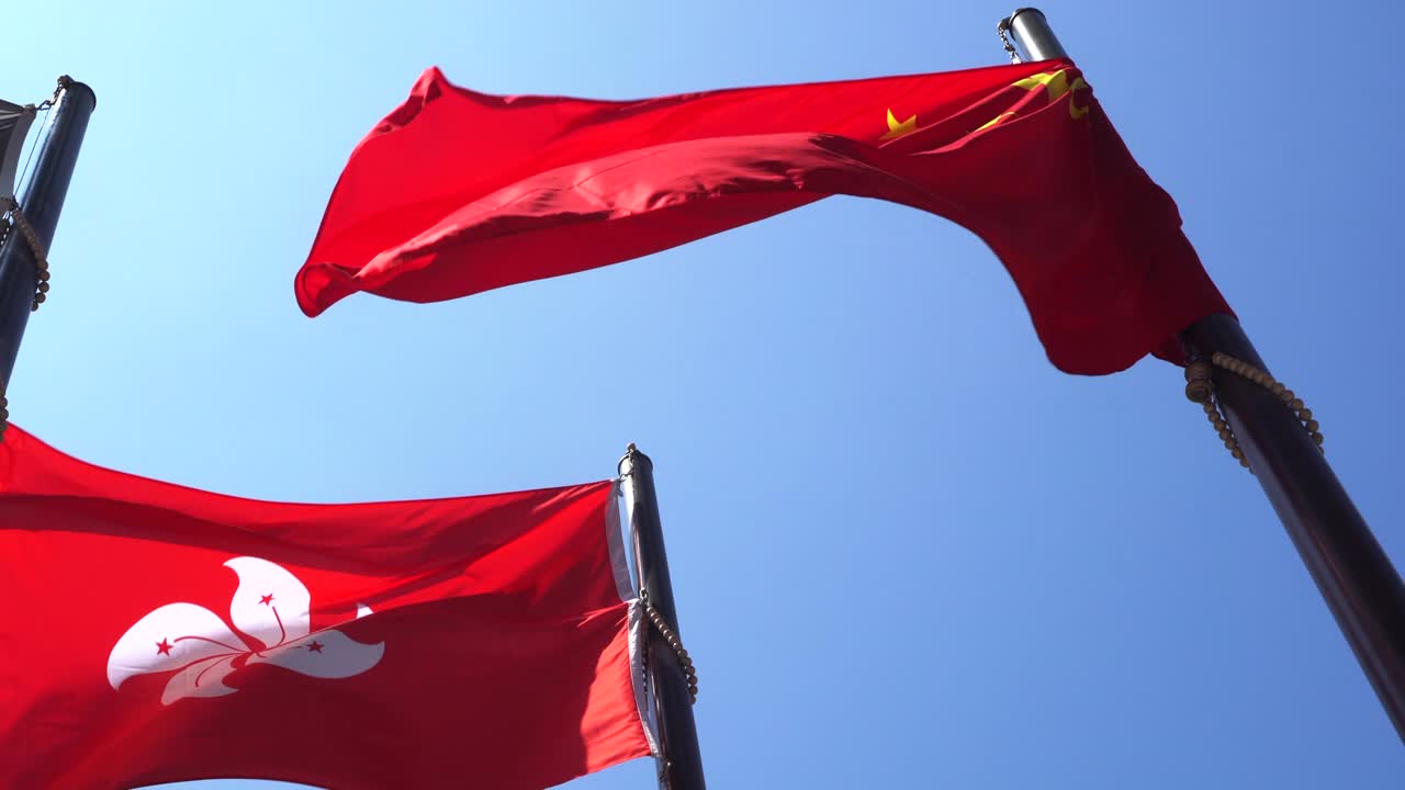 Hong Kong and Mainland China red flags in blue sky. Internal political affair conflict