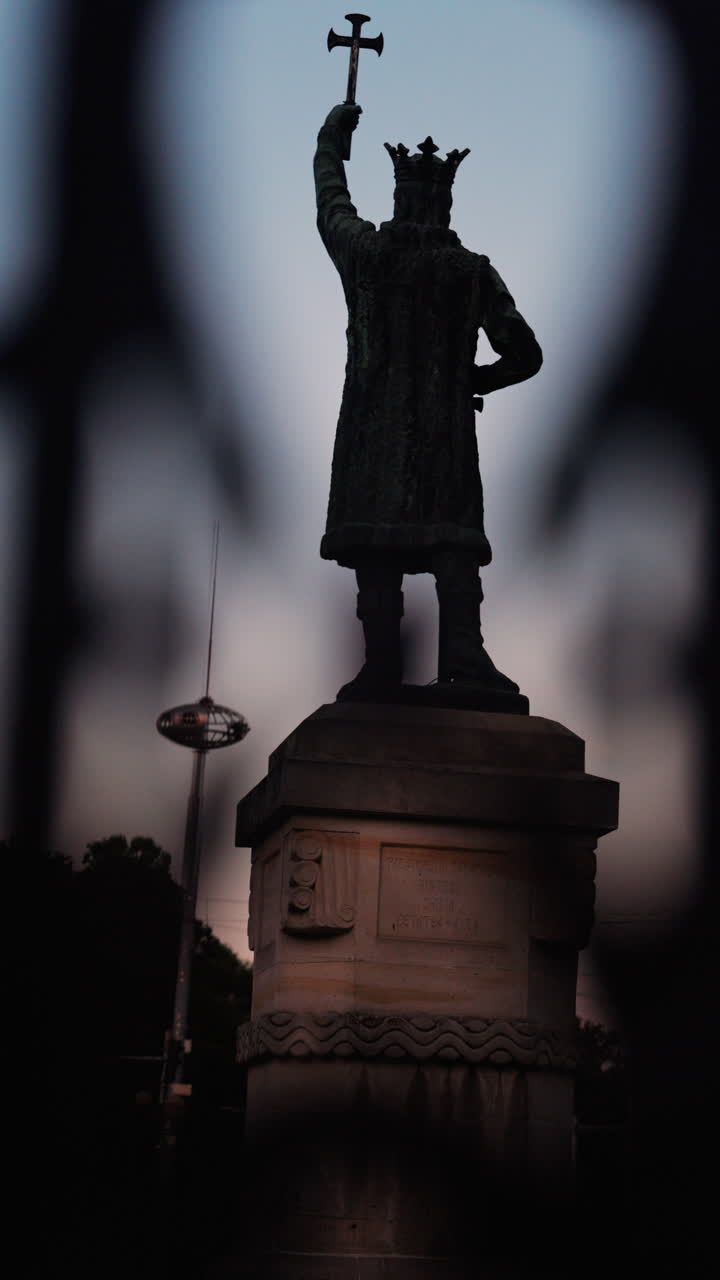 Chisinau, Moldova - June 15, 2025: Stephen the Great statue seen through the out-of-focus curves of a wrought-iron fence. Vertical