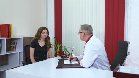 doctor talking to patient in office. senior male professional physician consulting female patient
