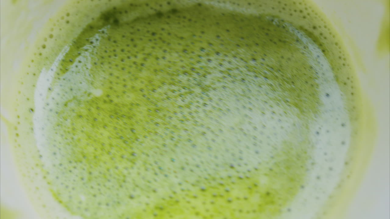 Close up of a smooth matcha latte with vibrant green foam in a white cup