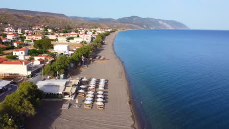 Greek Island longest Vatera beach lounging areas outside the local taverna or cafe surrounding mountains and turquoise sea, Lesvos Island, Drone shot
