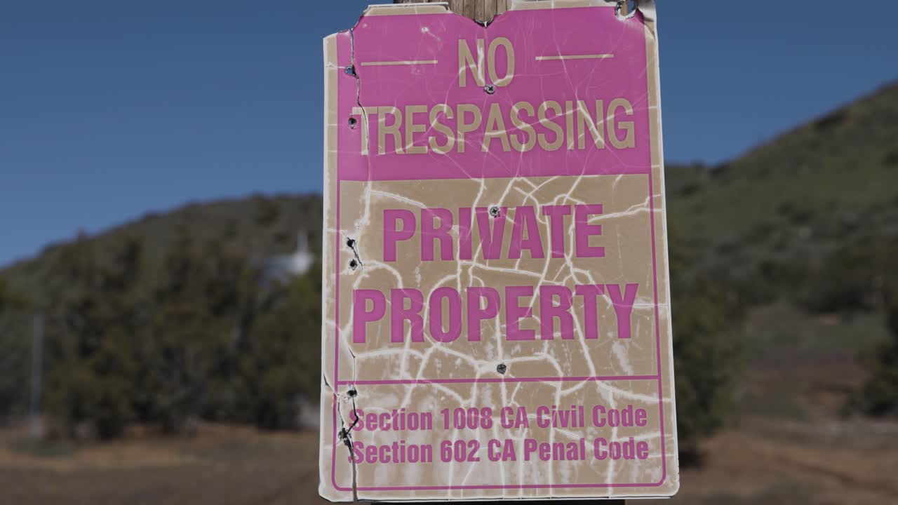 배경에 산이 있는 낡은 무단 침입 금지 및 사유 재산 표지판