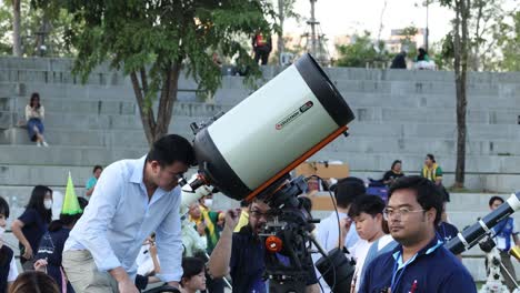 people assembling a telescope in a public area