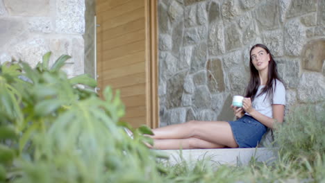 caucasian young woman sitting outside, holding cup, copy space