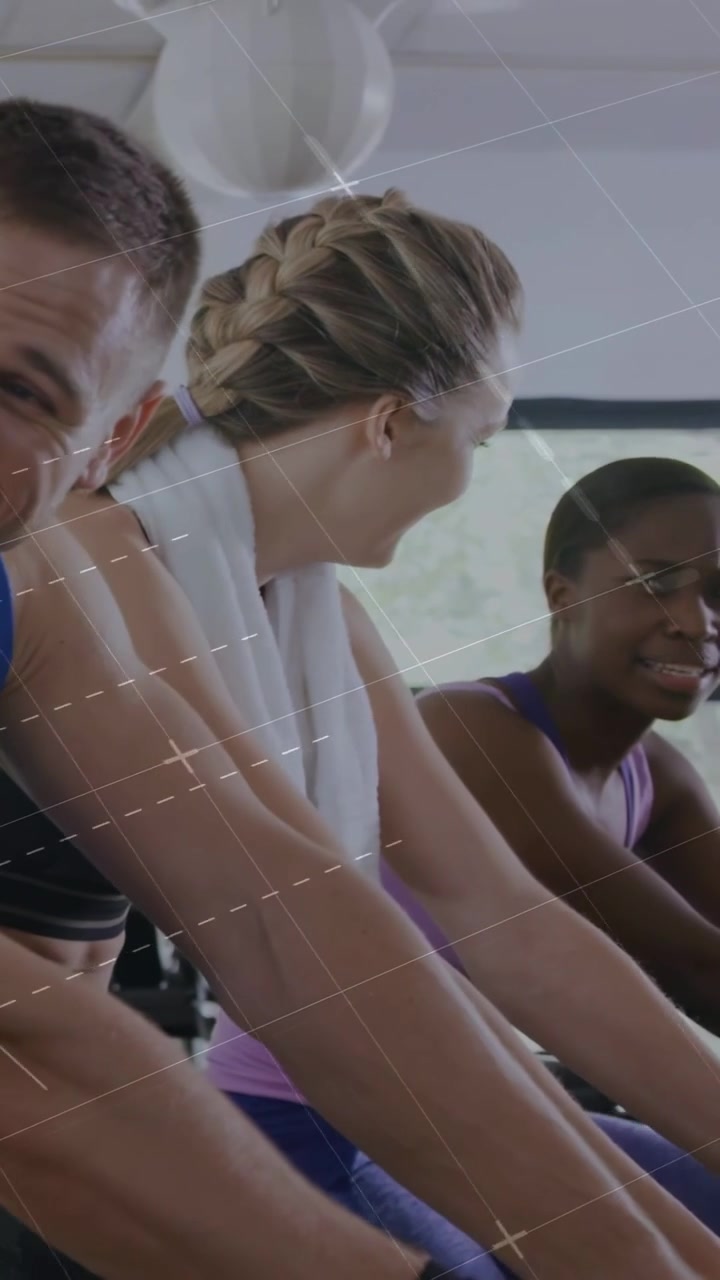 Vertikales Video: Frau in der Mitte dreht sich um, startet Diagramme über Fitnessradfahrern, während sie tritt und das Tempo verfolgt.