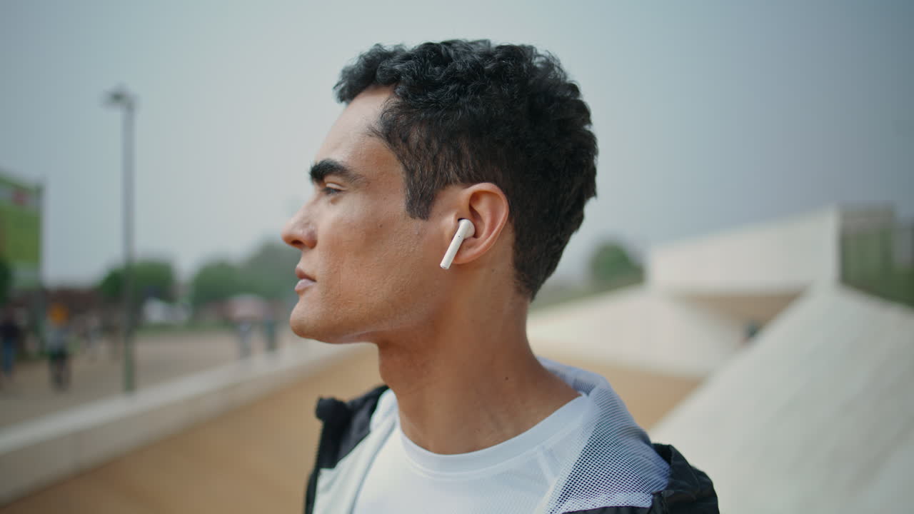 um tipo desportivo a ouvir música com fones de ouvido em close-up. um atleta em forma confiante a treinar.