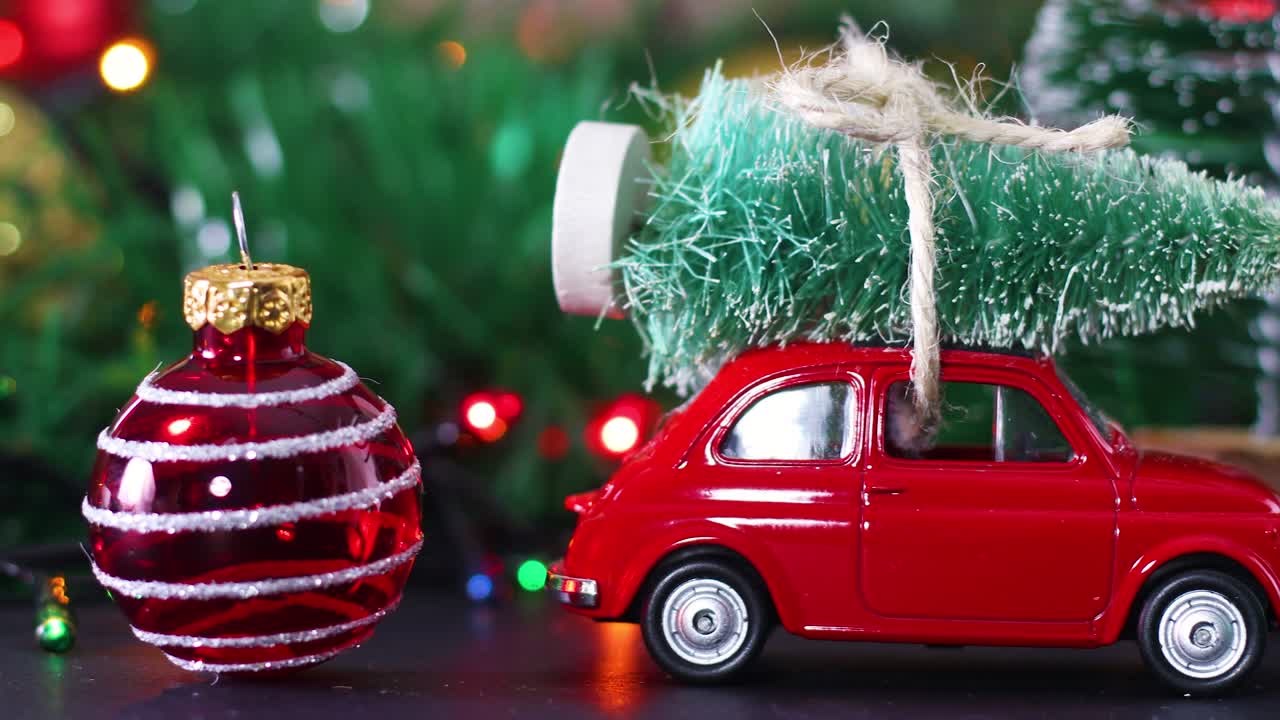 pequeño coche rojo con árbol de navidad en el techo y adornos de navidad y luces parpadeantes alrededor