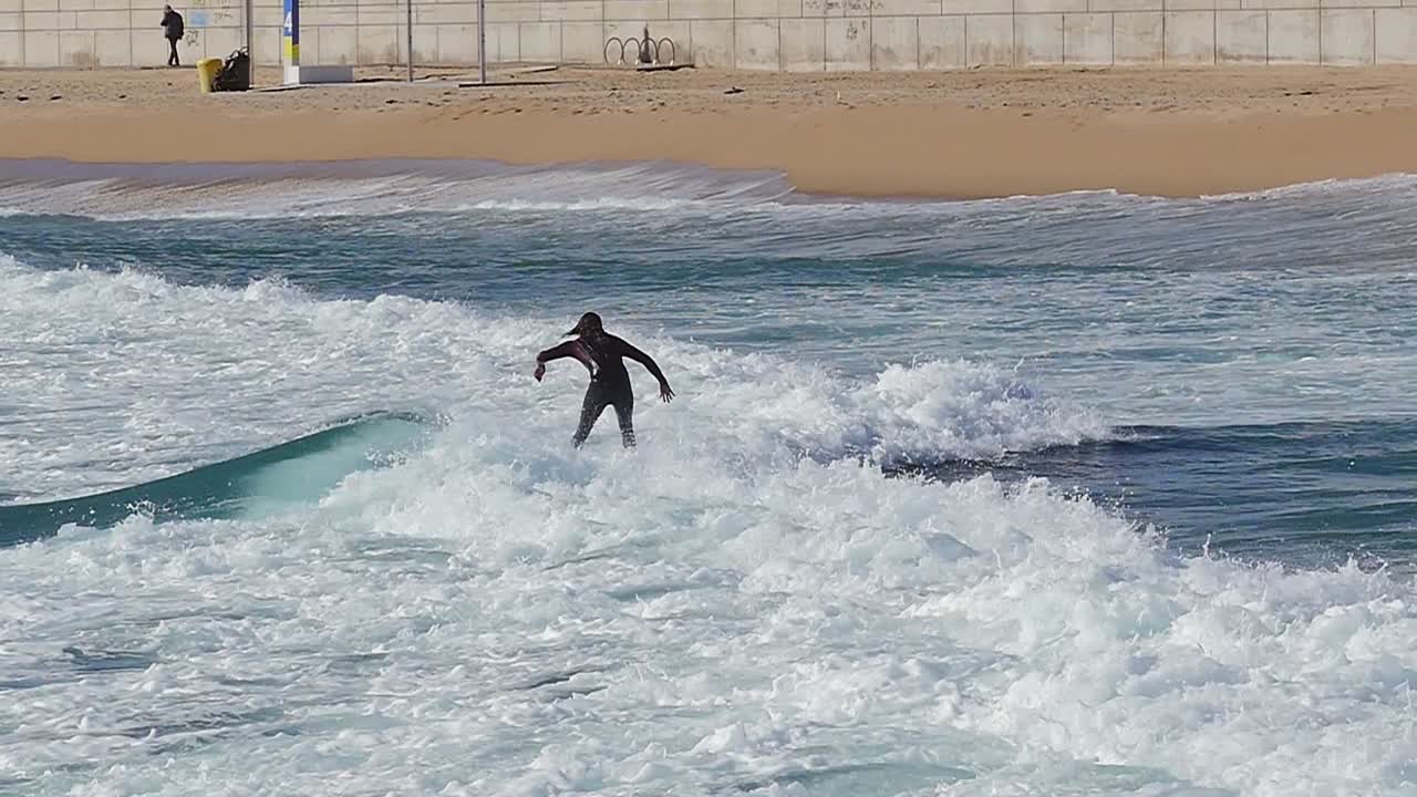 Slow motion (120fps): male surfer surfing the wave in Barcelona, Spain