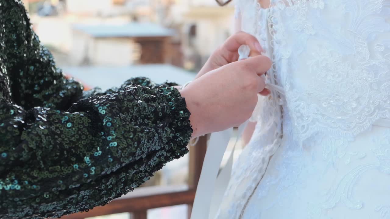 결혼식 의복 을 는 데 신부 를 도와주는 린 드레스 를 입은 여자 - 근접