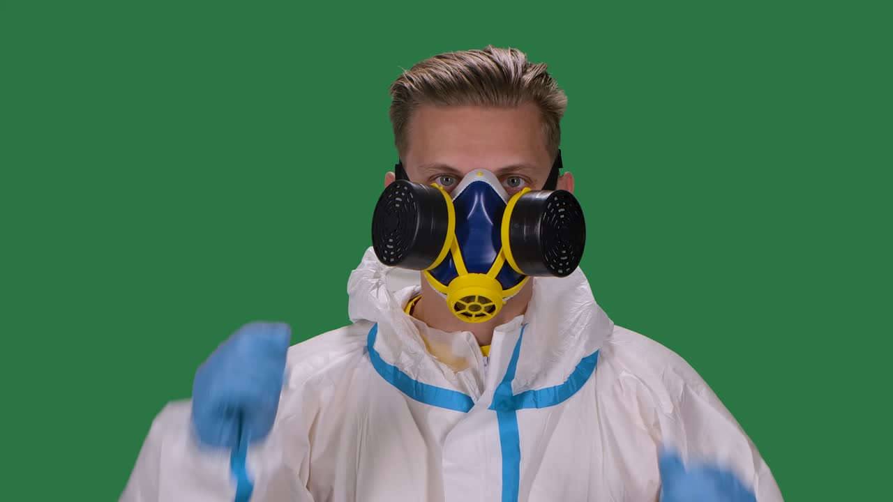 색 보호복과 수술 장갑을 입은 남성 바이러스 전문가의 초상화. 의료 호흡기를 착용하고 제거합니다. 녹색 스크린, 크로마 키, 느린 모션, 클로즈업.