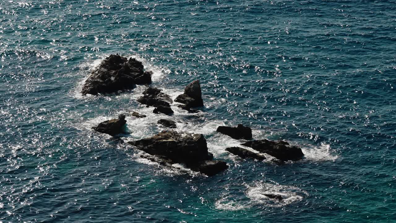 Waves crash against jagged rock formations along the sparkling Tangier coastline