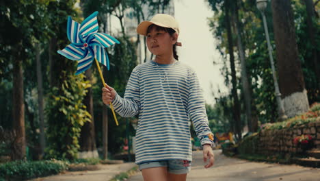 girl playing with a windmill in a park