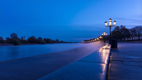 nighttime river promenade with illuminated streetlights and reflections