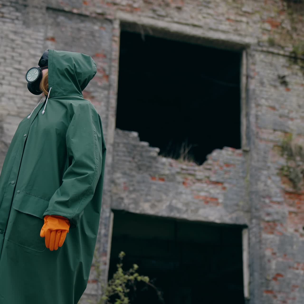 Persona con maschera antigas e tuta di sicurezza all'aperto. Uomo che indossa un respiratore e un'uniforme protettiva in piedi in un luogo post-apocalittico. Attacco chimico