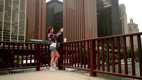 hermosa mujer haciendo una foto móvil de los rascacielos de la ciudad moderna