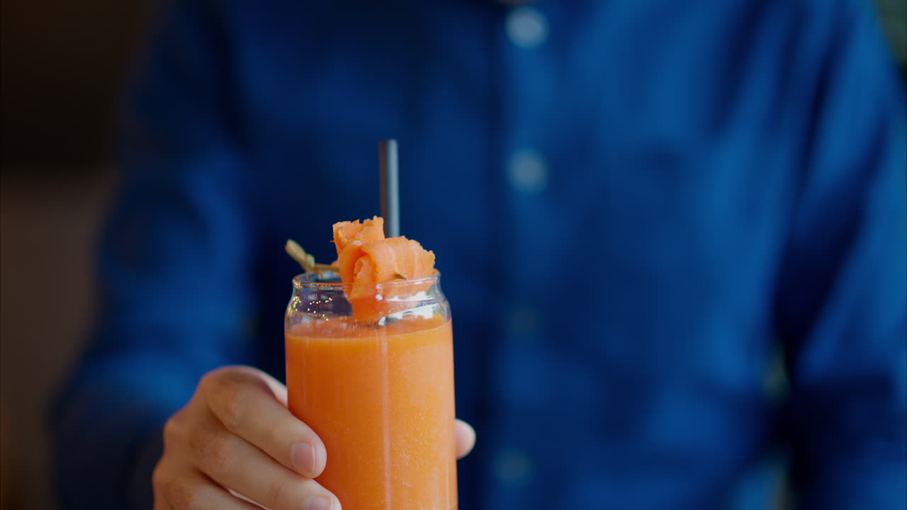 Uomo che beve succo di carota con una cannuccia in un ristorante
