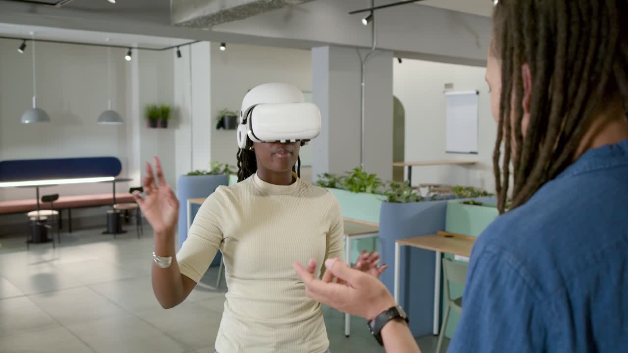 African American coworkers demoing VR in office, woman following man's gestures with white headset
