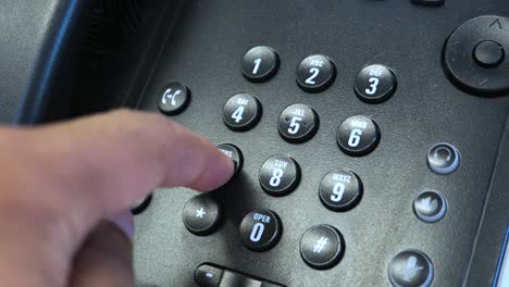 Close-up-of-Adult-male-hand-using-finger-to-press-phone-numbers-on-desk-phone-in-an-office