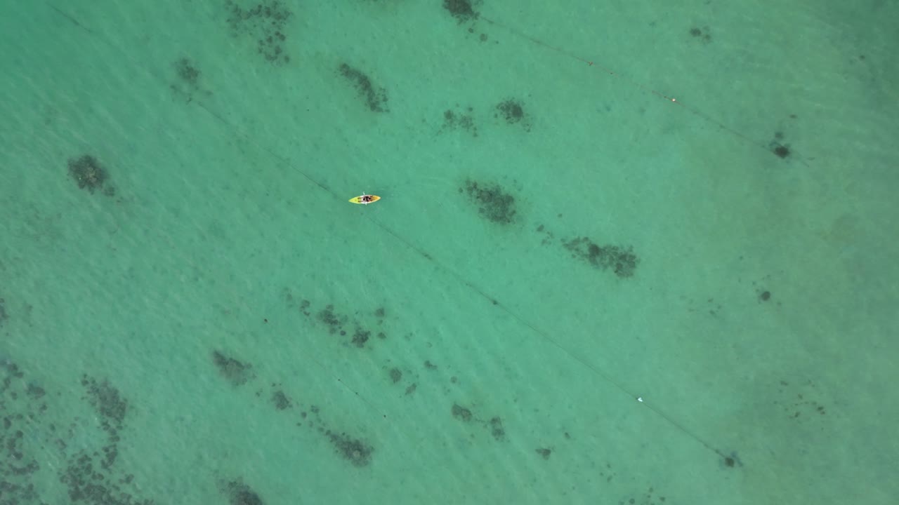 Persona in kayak su una laguna cristallina color smeraldo, ampia ripresa aerea.