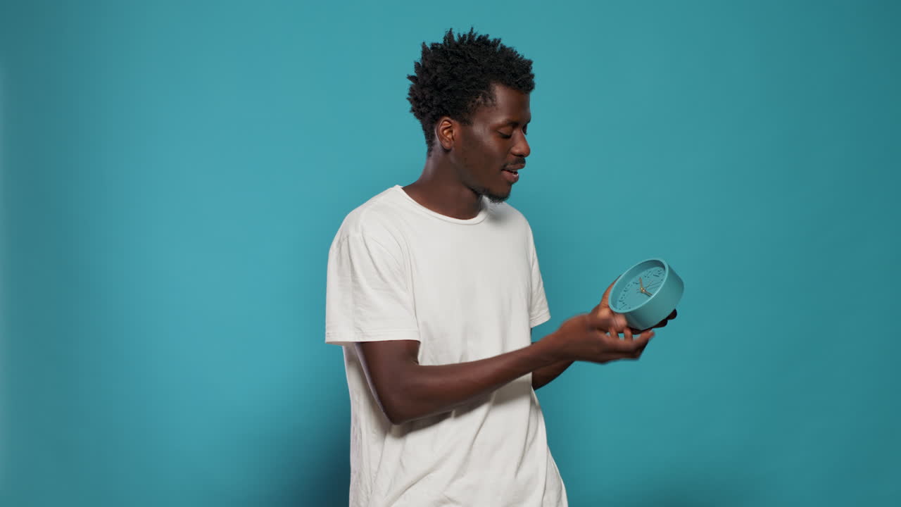 Portrait of man holding wall clock and talking to camera