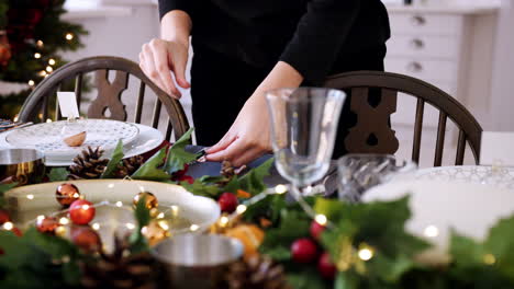 Sección-Media-De-Una-Mujer-Poniendo-Cubiertos-De-Plata-En-Una-Mesa-De-Comedor-Decorada-Para-La-Cena-De-Navidad,-Enfoque-Selectivo