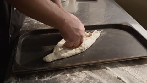 extendiendo la masa en una bandeja para hornear para cocinar khachapuri